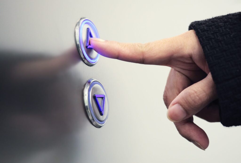 Image of hand pressing an elevator up button